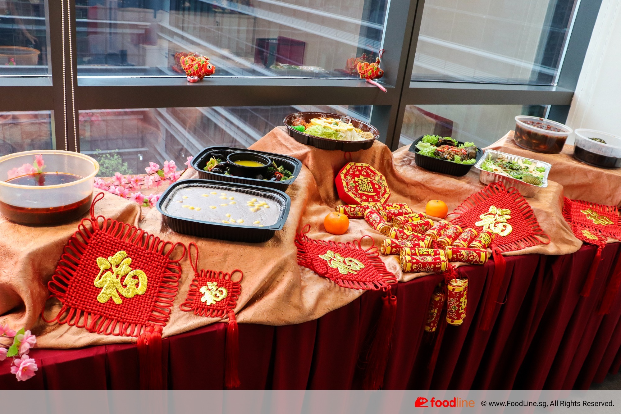 CNY festive buffet spread with traditional decorations, prosperity symbols, and festive dishes on a red and gold-themed table.