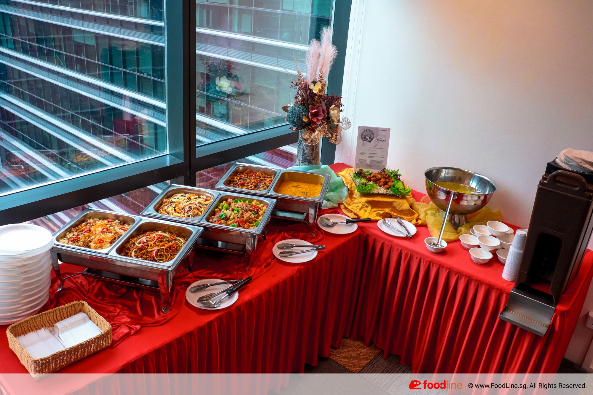 CNY buffet setup with festive dishes, red tablecloth, and decorations.